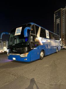 un autobús azul estacionado en un estacionamiento por la noche en فندق اوبن هوتيل مكه المكرمه en La Meca