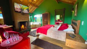 Dormitorio verde con cama y chimenea en Chalés Mirante das Pedras, en Monte Verde