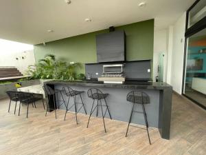 eine Küche mit einer Theke mit vier Barhockern in der Unterkunft Lujo y comodidad en Zona Norte in Santa Cruz de la Sierra