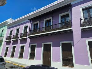 een paars gebouw met balkons in een straat bij KASA San Francisco 1 in San Juan