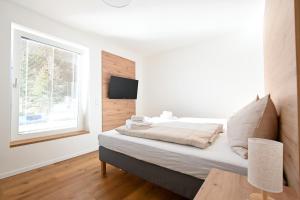 ein weißes Schlafzimmer mit einem Bett und einem Fenster in der Unterkunft Arton Lachtal - Apartments Steiermark in Lachtal