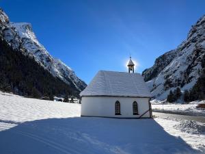 una pequeña capilla blanca con un campanario en la nieve en Gschlössle Ferienwohnungen, en Jerzens