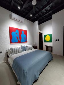 CASA ROMA Hotel Boutique في El Tamarindo: غرفة نوم بسرير كبير ولوحتين على الحائط