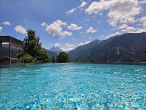 una piscina de agua azul con montañas en el fondo en Hotel Kompatscherhof, en Luson