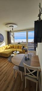 a living room with a yellow couch and a table at Gerlitzen-Apartments in Kanzelhöhe