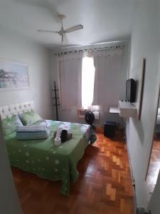 1 dormitorio con 1 cama verde y TV en Aconchegante Ap Copacabana, en Río de Janeiro
