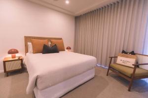 a bedroom with a large bed and a chair at The Beach Oasis ~ Dune in Kingscliff