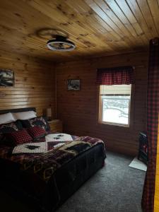 een slaapkamer met een bed in een houten hut bij The Lazy Bear Cabin in Long Lake