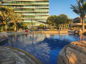 a swimming pool in front of a large building at Sea View 1BR Al Raha Beach in Abu Dhabi