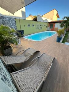 uma piscina com duas espreguiçadeiras ao lado de um edifício em Serra Negra Pousada Spa em Guarapari