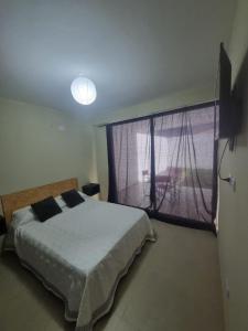 a bedroom with a bed and a large window at Deparcasa in Yerba Buena