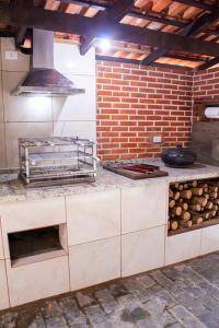 eine Küche mit Herd und Ziegelwand in der Unterkunft Casa Pedra & Mar - Paraiso na Praia de Caieiras in Guaratuba + 14 Fotos