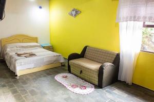 ein kleines Schlafzimmer mit einem Bett und einem Stuhl in der Unterkunft Casa Pedra & Mar - Paraiso na Praia de Caieiras in Guaratuba