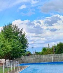 a blue swimming pool with a fence and trees at Don Romulo in Tupungato