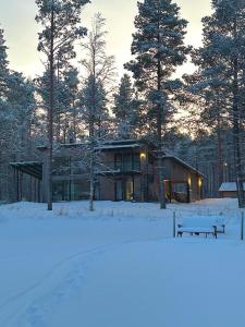 una casa en la nieve con un banco delante en Villa Hekuma en Keränen