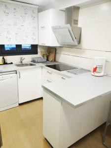 una cocina blanca con armarios blancos y fregadero en La Casa de la Ría, en Collera