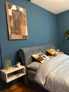 a bedroom with blue walls and a couch with pillows at LP Premium Studio in Niš +6 photos