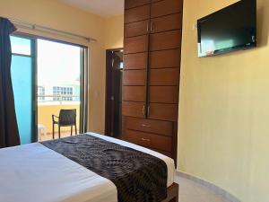 a bedroom with a bed and a flat screen tv at Hotel San Miguel Playa del Carmen in Playa del Carmen