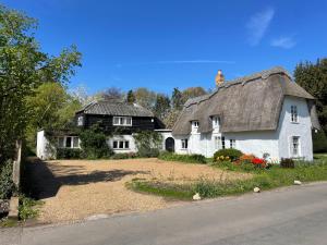 an old white house with a thatched roof at Beautifully appointed one-bedroom cottage in Shepreth