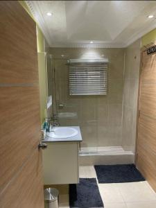 a bathroom with a sink and a shower and a tub at The Cameron @ Phoenix Park in Portmore