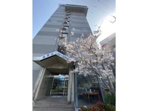 a building with a flowering tree in front of it at Hotel New Yutaka - Vacation STAY 35266v in Izumi-Sano