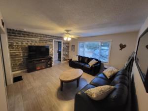 sala de estar con sofá, mesa y chimenea en BowLakeHouse - Lakefront Cottage with Beach en Bancroft