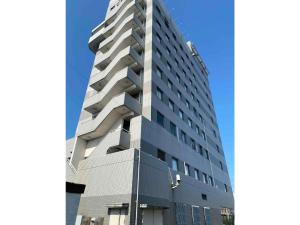 a tall grey building with a blue sky in the background at Hotel New Yutaka - Vacation STAY 35263v in Izumi-Sano