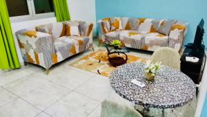 a living room with two couches and a table at Appartement Meublé Bonamoussadi Douala in Deido