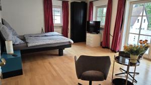 a bedroom with a bed and a tv and a chair at Ferienhaus Weilheim mit Garten Spiel und Spass in Weilheim in Oberbayern