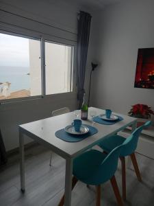 mesa de comedor con 2 sillas azules y ventana en Loft espectacular vista al mar, en Sitges