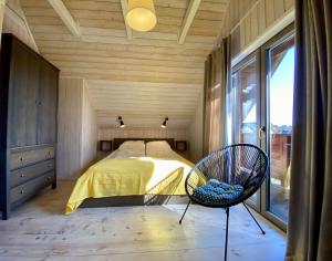 una camera da letto con un letto, una sedia e una finestra di Domki Poezja Ciszy a Dębki