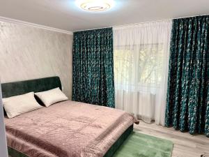 a bedroom with a bed and a window with curtains at ELITE APARTMENT in Buzău