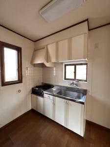 eine Küche mit weißen Schränken, einem Waschbecken und 2 Fenstern in der Unterkunft Hoshi no Machi No, 177 - Vacation STAY 39992v in Tsumagoi