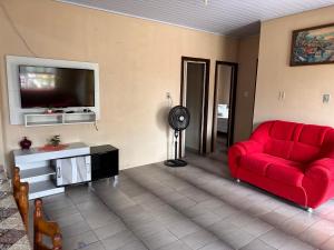 a living room with a red couch and a flat screen tv at Casa albatroz Imbé in Imbé