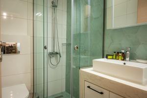 bagno con doccia in vetro e lavandino di White Luxury Apartments a Kateríni