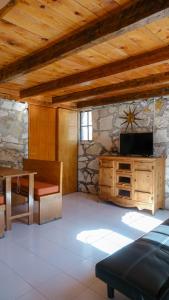 a living room with a tv on a stone wall at Hotel Real de San Antonio in Estanzuela