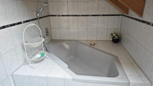a white tub in a bathroom with a basket at Ferienhaus Weilheim mit Garten Spiel und Spass in Weilheim in Oberbayern