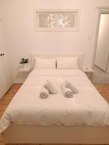 ein weißes Bett mit zwei Paar Handtüchern darauf in der Unterkunft CASA Di TRE in Thessaloniki