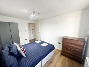 - une chambre avec un lit bleu et une commode en bois dans l'établissement Camden Apartment, à Londres