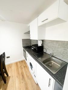 - une cuisine avec des placards blancs et un évier dans l'établissement Camden Apartment, à Londres