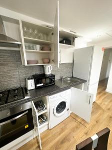 La cuisine est équipée de placards blancs, d'une cuisinière et d'un évier. dans l'établissement Camden Apartment, à Londres