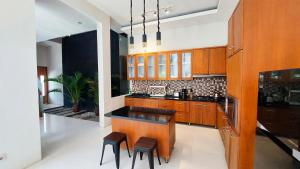 eine Küche mit Holzschränken und eine Insel mit Hockern in der Unterkunft Meninting Beach Villa, 3 bedroom in Montongbuwoh