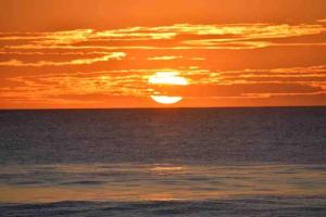 um pôr-do-sol sobre o oceano com o sol no céu em Nirvana Beach Home em Paraíso