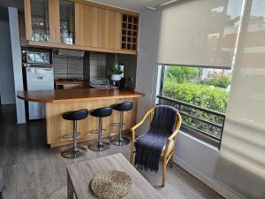 a kitchen with a bar with stools and a window at Espectacular Bahía Bonita Depto 12 in Concón