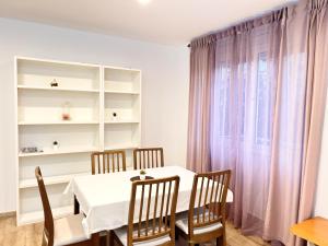 a dining room with a white table and chairs and a window at Josep Tarradellas Entire Apartment in Sabadell
