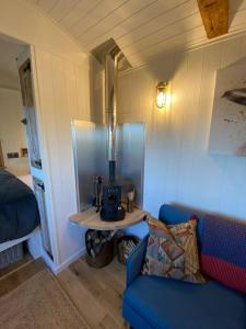 a living room with a blue couch and a table at Luxury Shepherd Hut in Kelham