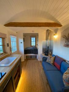 a living room with a blue couch and a bed at Luxury Shepherd Hut in Kelham