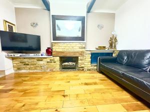 a living room with a black leather couch and a fireplace at Lime Tree House in Heston