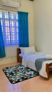 two beds in a room with blue curtains and a rug at AF HOMESTAY in Dungun