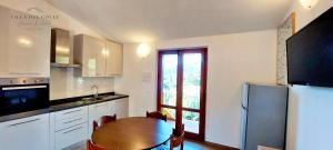 a kitchen with a wooden table and a refrigerator at Villa del Colle Charme e Relax in Procchio